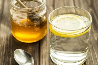Стакан медовой воды с ложкой меда и корицей на деревянном столе