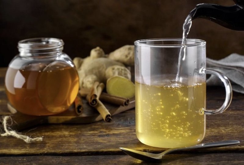 Стакан медовой воды с ложкой меда и корицей на деревянном столе