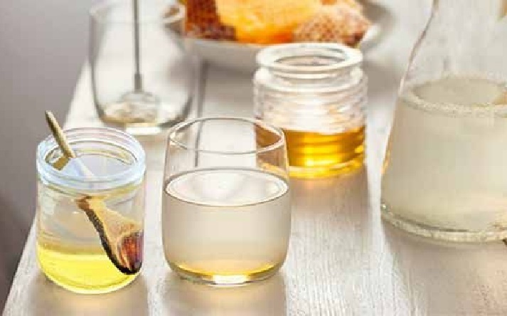 Стакан медовой воды с ложкой меда и корицей на деревянном столе